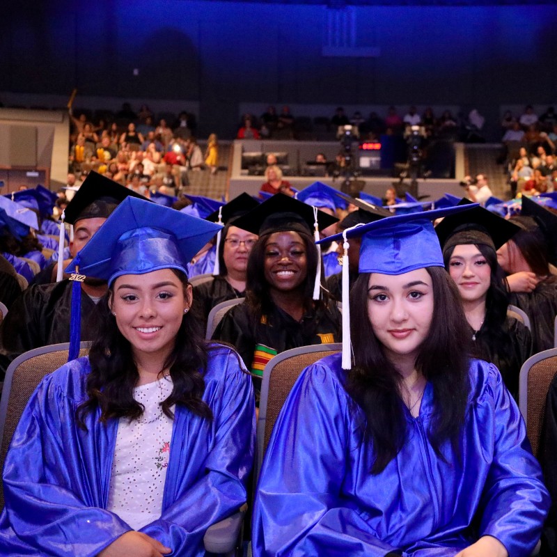 Graduates sitting and smiling at their ceremony