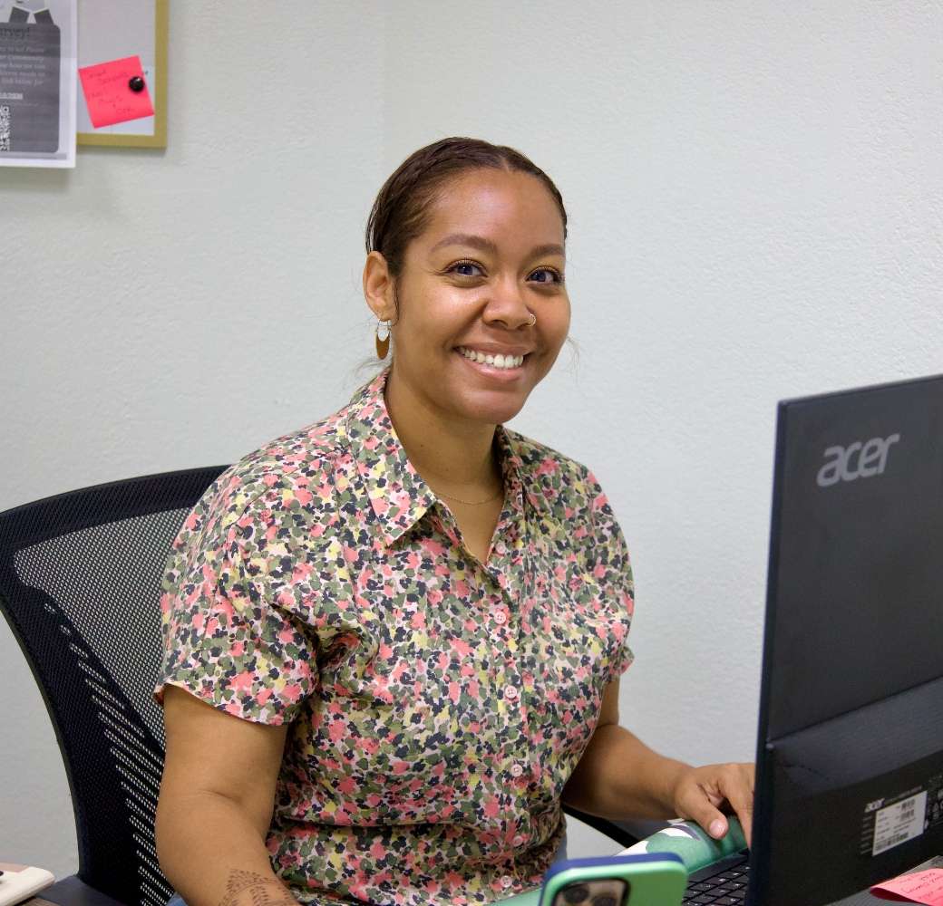 Employee smiling while sitting at a desk in front of a computer