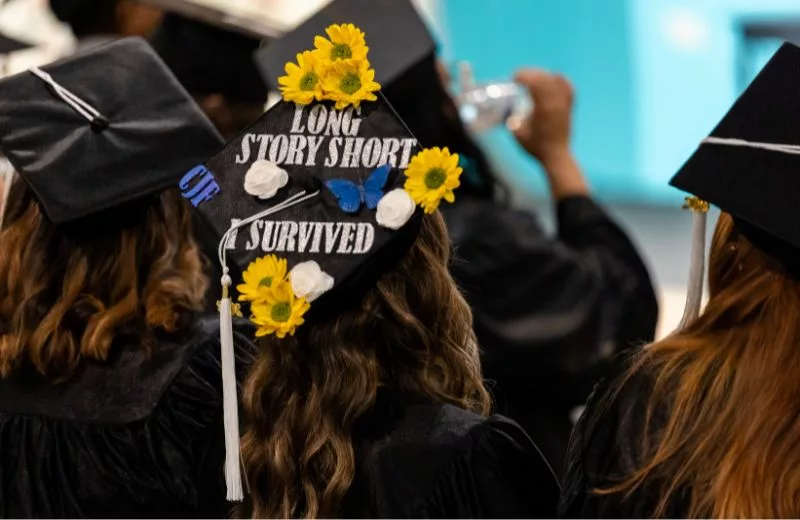 A decorated graduation cap that reads, "Long story short, I survived"