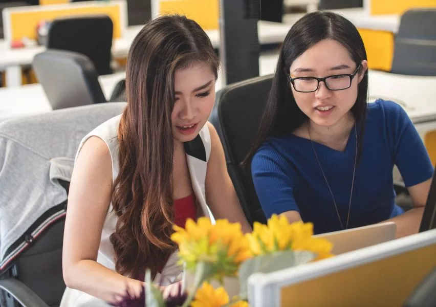 Advisor sitting with a student at a laptop, reviewing resources