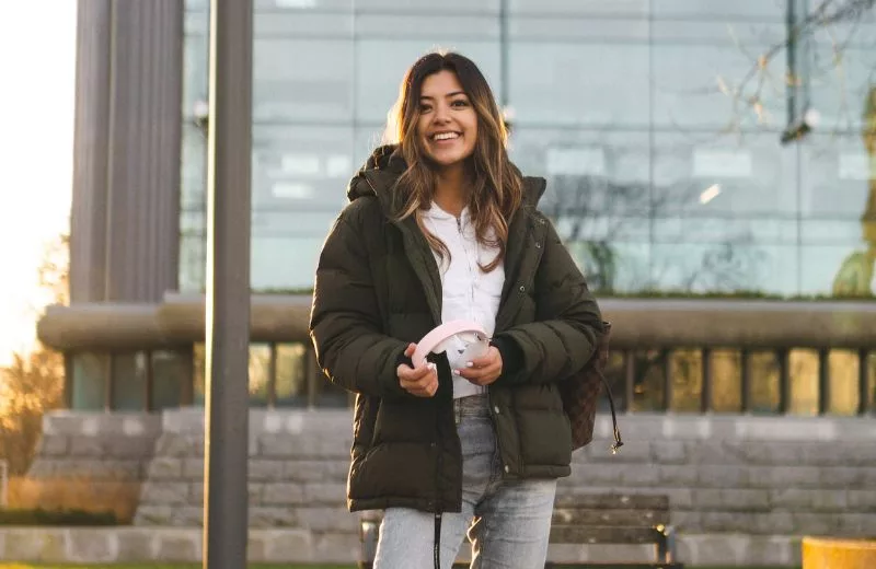 Student standing outside, smiling on the campus of her college