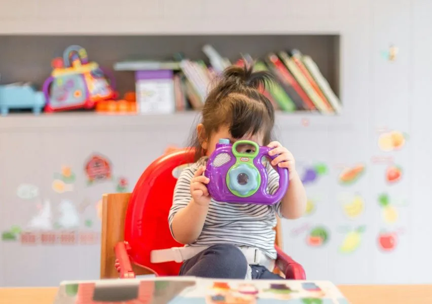 Child happily playing with a toy camera