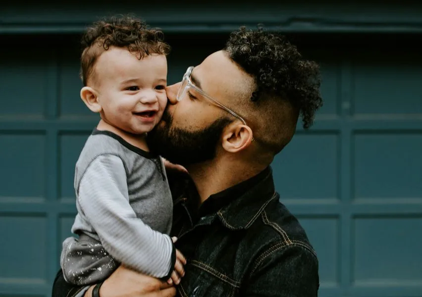 Young father holding and kissing his son