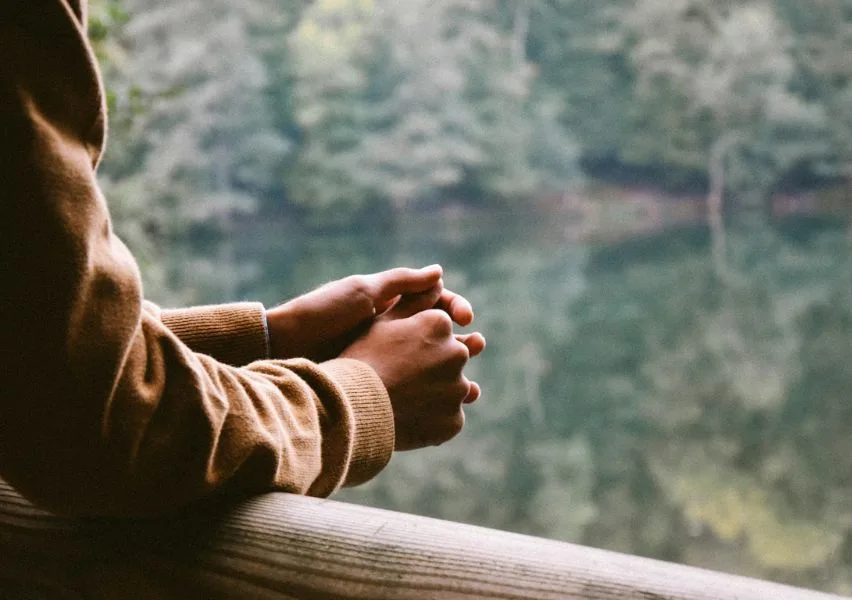 Someone leaning against a rail with hands folded