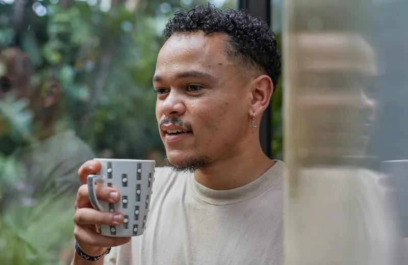 Student taking a moment to standing outside and drink coffee by himself