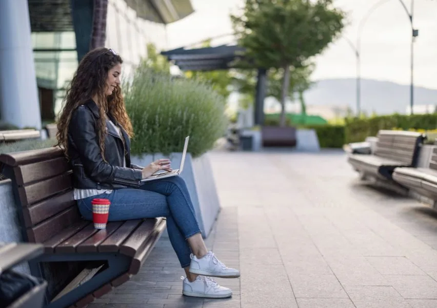 Student working on her online class outside on a park bench