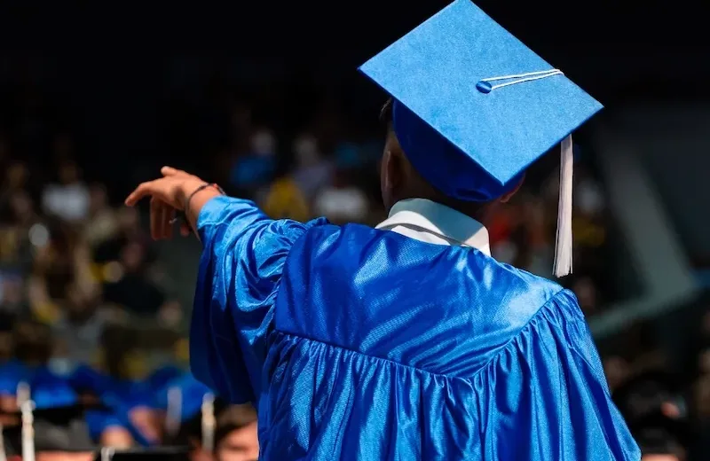 Man pointing out to crowd at high school graduation ceremony