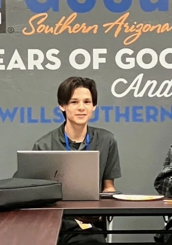 A student sitting at a table with his laptop working on an online class.