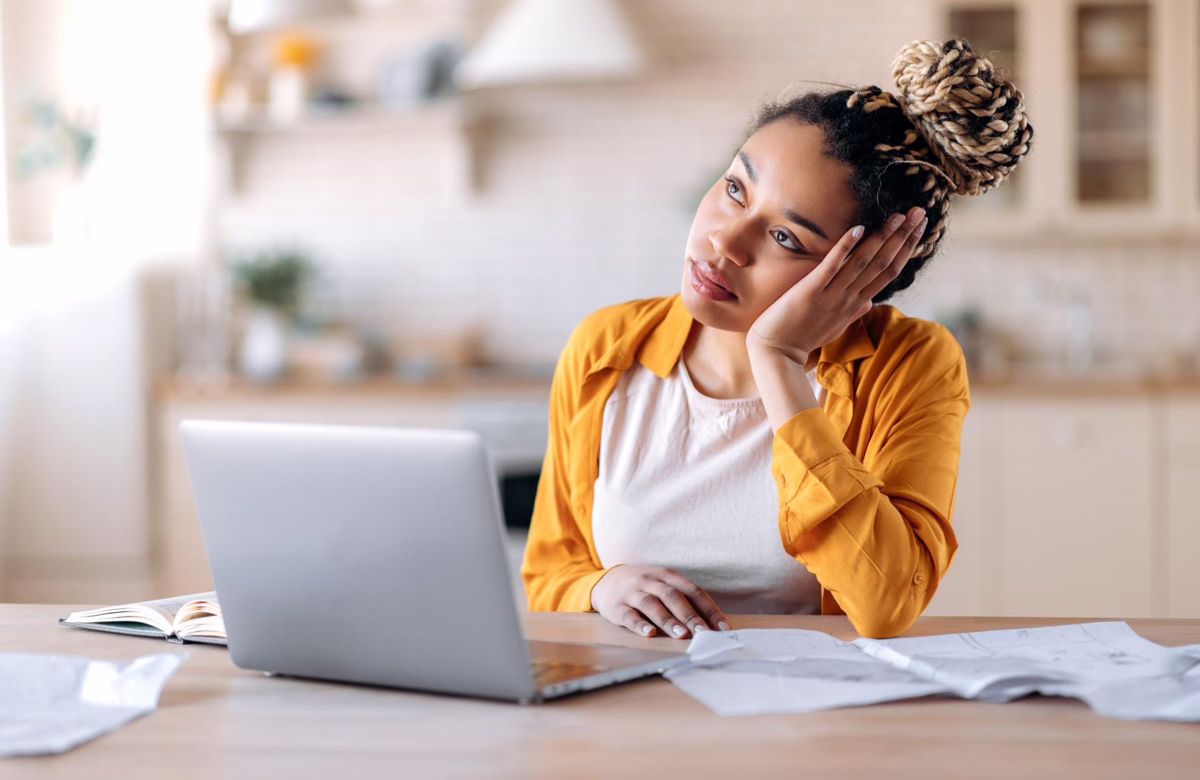 Tired emaciated female student, sits at her desk with her head on her hand, tired of working online or distance learning, thinking about weekend or vacation, need a rest